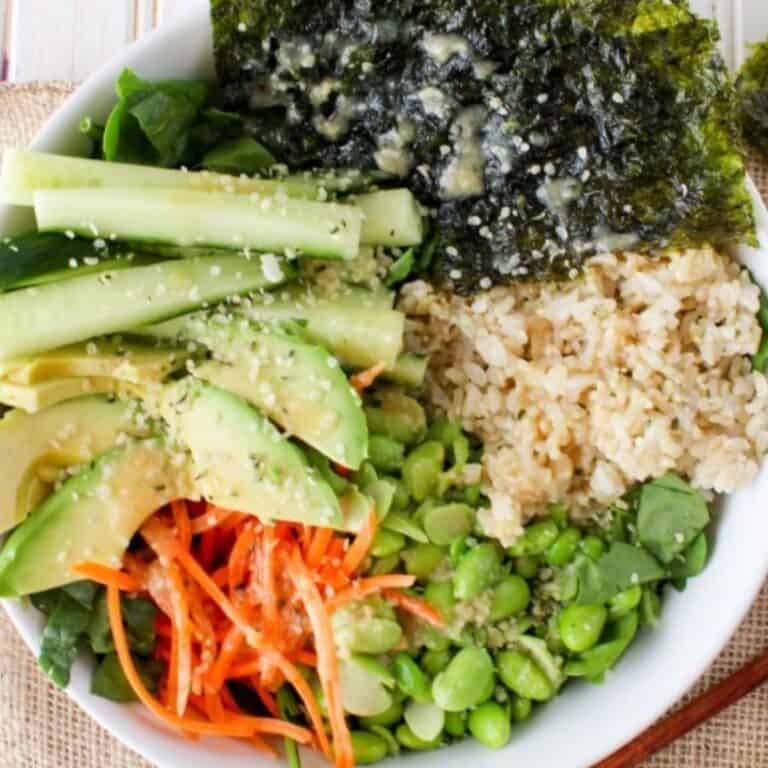 Vegetarian sushi salad bowl with rice, edamame, avocado, veggies, and miso dressing.