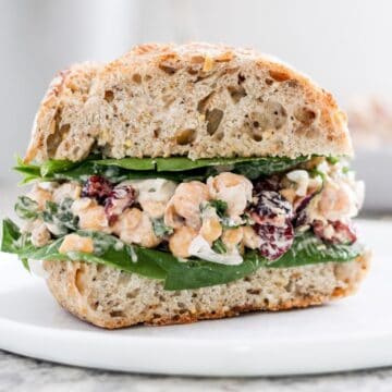 Creamy vegan chickpea salad sandwich with dried cranberries.