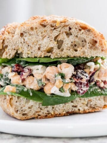Creamy vegan chickpea salad sandwich with dried cranberries.
