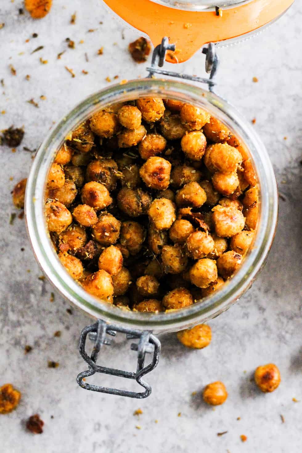 Vegan cheesy herb roasted chickpeas in mason jar against grey background.