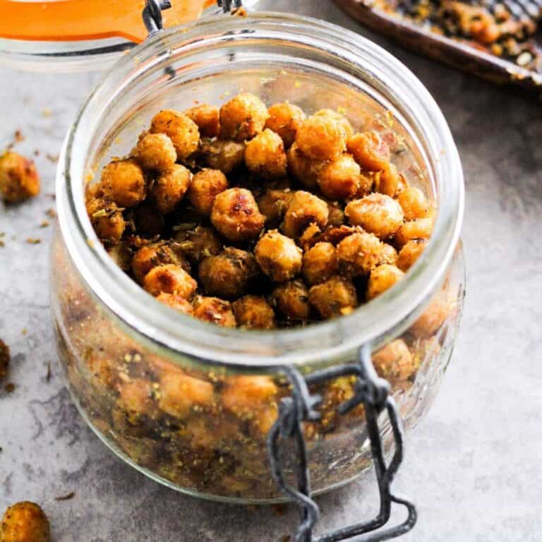 Cheesy roasted chickpeas with nutritional yeast in a glass jar.