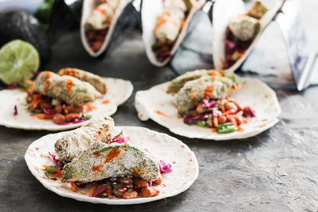 Crunchy avocado tacos make a delicious plant-based lunch or dinner entree that the entire family will love! Served with colorful vegan pinto bean slaw.