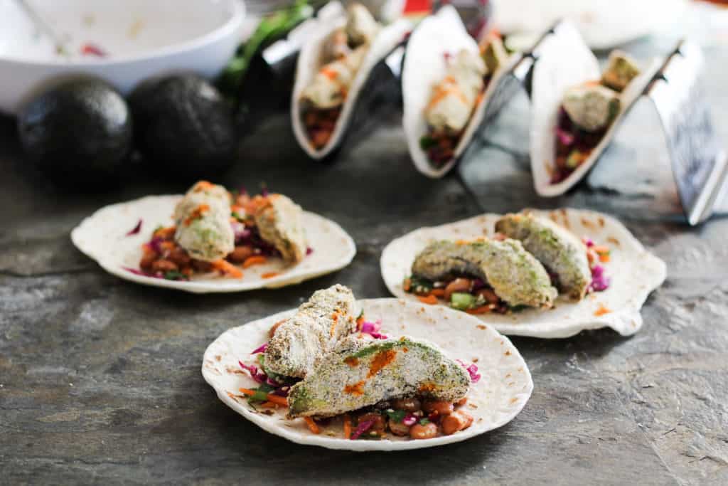 Crunchy avocado tacos make a delicious plant-based lunch or dinner entree that the entire family will love! Served with colorful vegan pinto bean slaw.