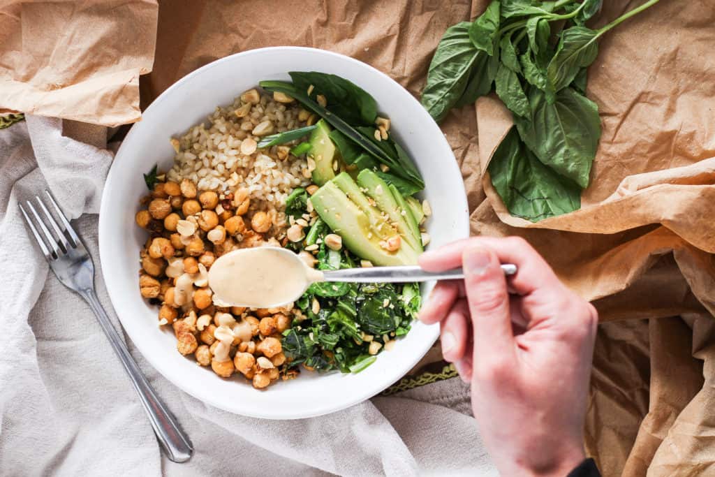 Chickpea bowls served with spicy peanut sauce and seasonal sesame oil greens for the delicious flavors of Thai take-out from home. Easy plant-based recipe!