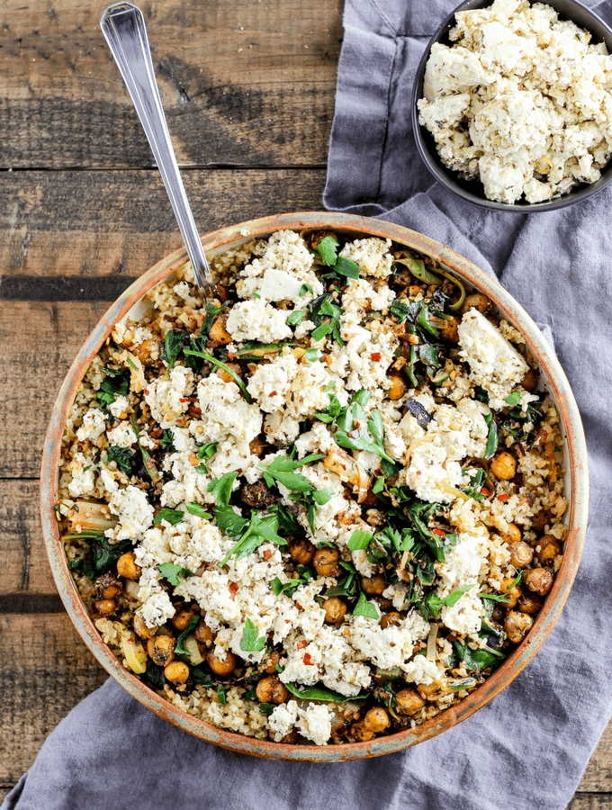 This comforting Mediterranean main dish needs to be in your weeknight rotation! Greek-seasoned roasted chickpeas served with vegan tofu feta, spicy greens, and freekeh.