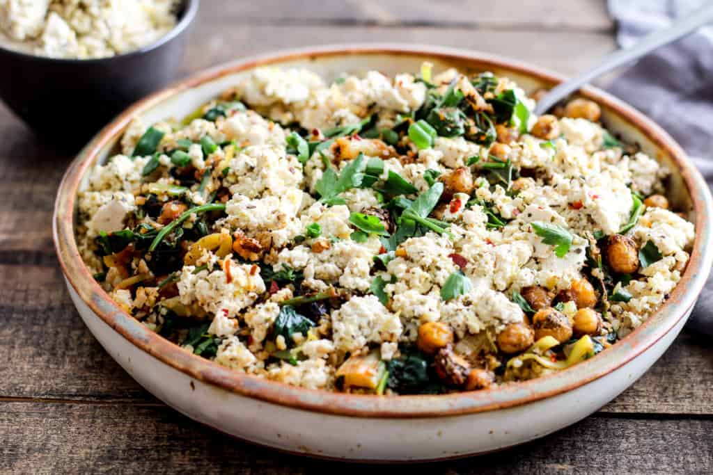 Comforting and delicious Greek roasted chickpeas served with vegan tofu feta, spicy greens, and freekeh. You need this dinner in your weeknight rotation!