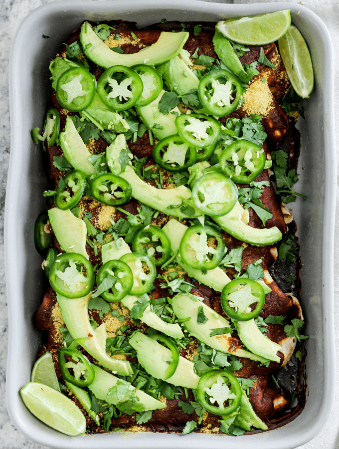 Vegetarian meal prep spinach mushroom walnut enchiladas in a gray casserole dish.