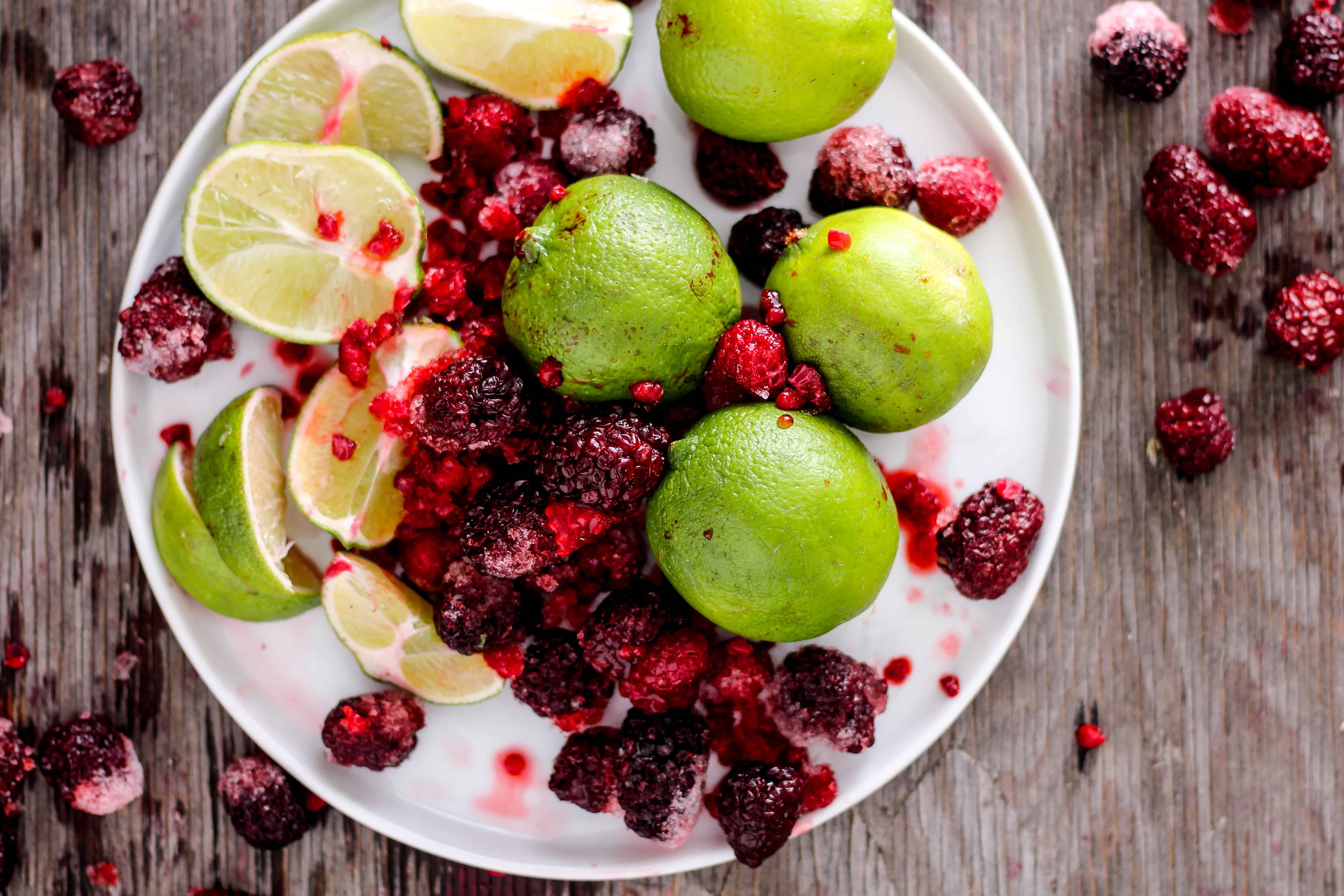 Lime and frozen berries on white plate.