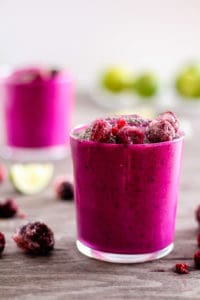 Hot pink dragon fruit smoothie in glass with berries.