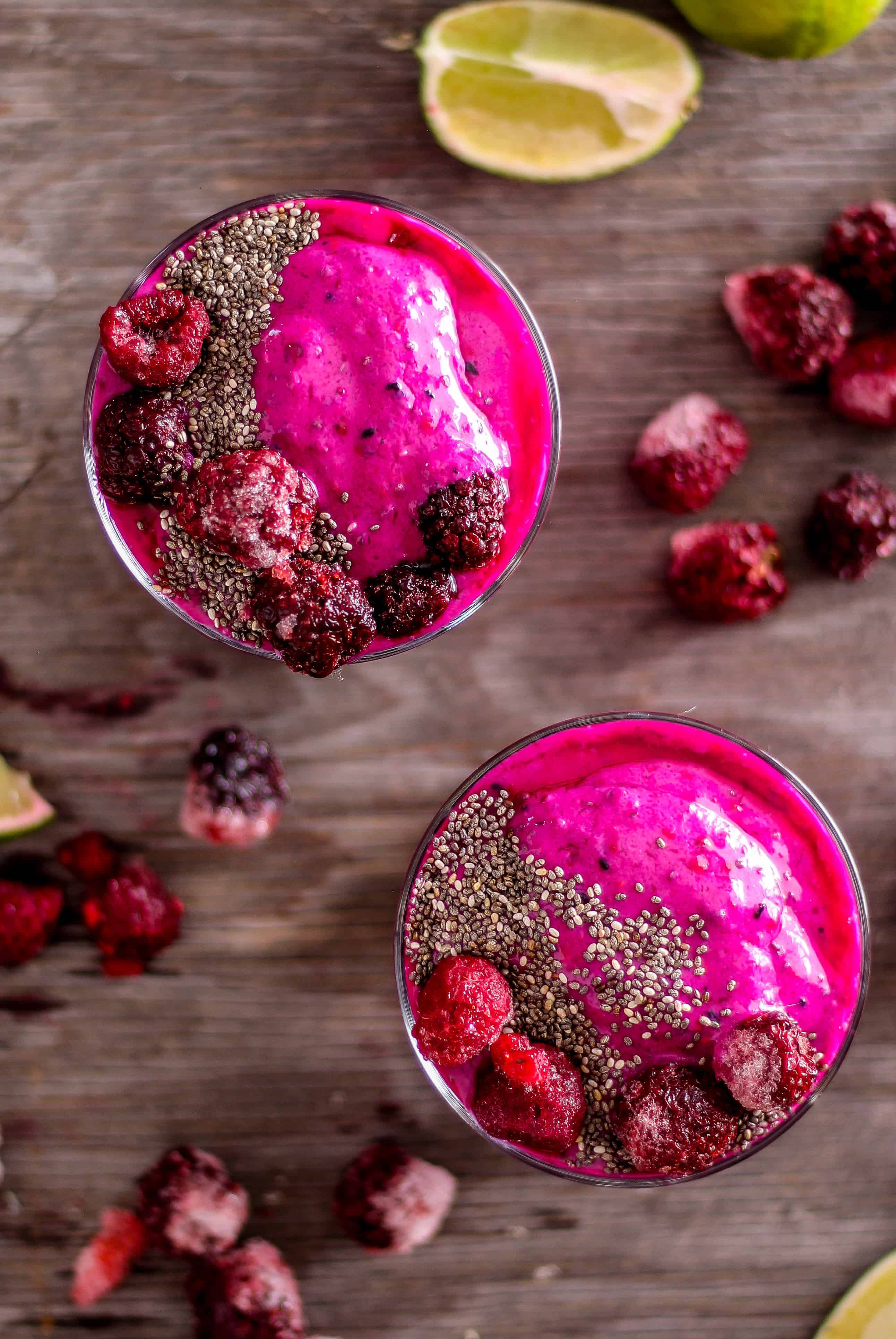 Overhead image of hot pink smoothies with berries and lime.