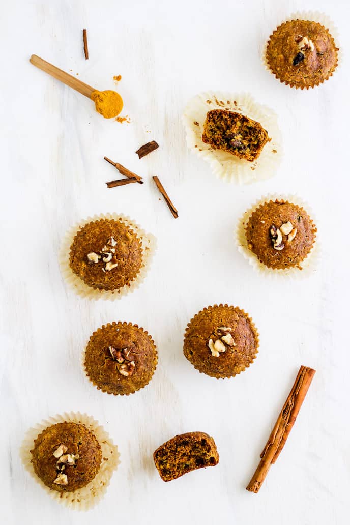 Overhead shot of gluten-free golden milk muffins arranged against white backdrop with spoonful of turmeric.