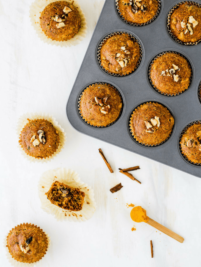 Muffin tin with gluten-free golden milk muffins against a white backdrop and a spoonful of turmeric.