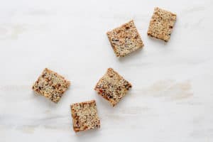 Sesame date bars arranged in curved line against white backdrop.