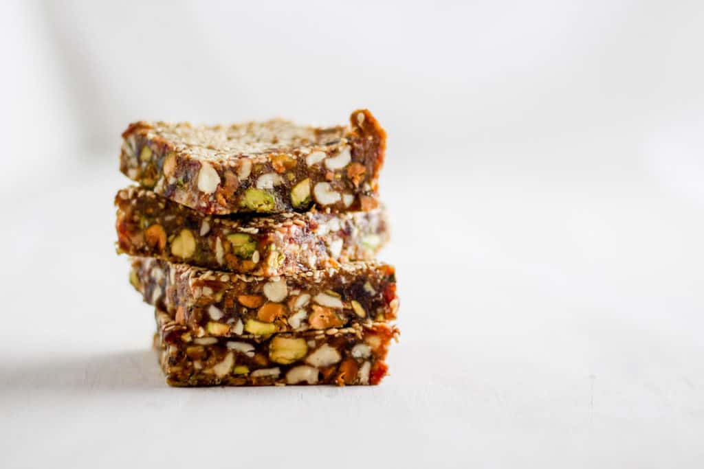 Stack of sesame date bars against white backdrop.