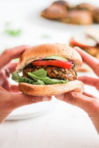 Moroccan Chickpea Burger held in hands with white backdrop.