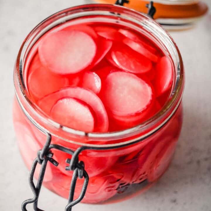 Square image of quick pickled radishes in a jar.