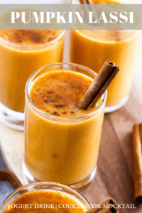 Pumpkin lassi drinks in small glasses with cinnamon stick garnish and text that reads, "pumpkin lassi."