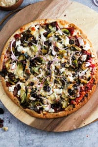 Sliced brussels sprouts pizza on wood serving board.