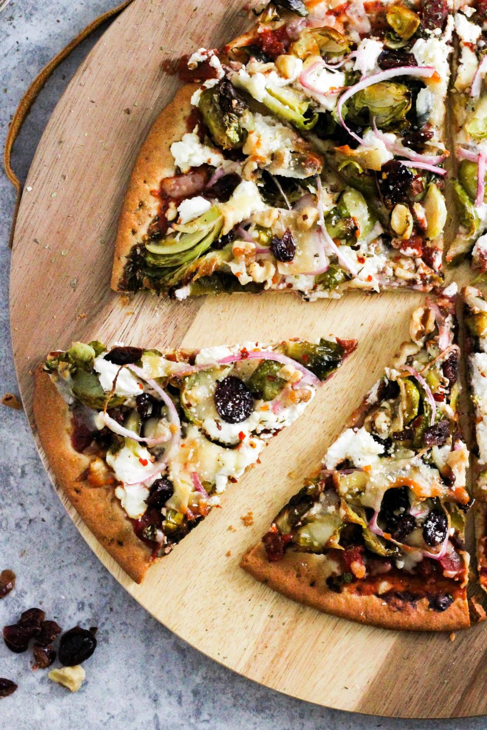 Sliced brussels sprouts pizza on wood serving board.