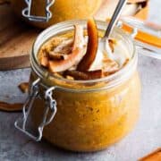 Pumpkin overnight oats in a glass jar with coconut strips and coconut cream garnish.