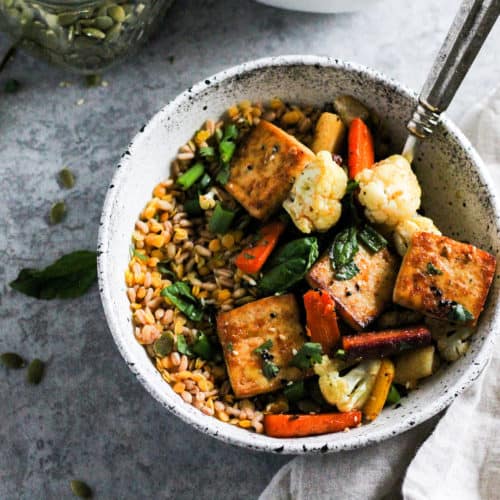 Sheet pan tofu bowls in white stone bowl with herbs and cream linen napkin.