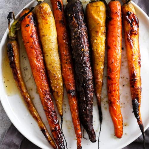 Roasted rainbow carrots on white plate with grey napkin.