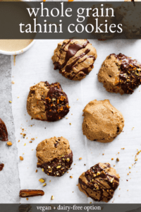 Tahini cookies on parchment paper. Some cookies are dipped in chocolate. Small bowl of tahini in corner.