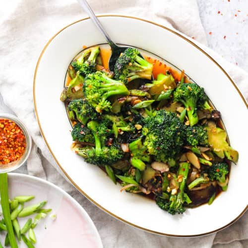 Low waste broccoli stem stir fry on white platter with ivory napkin.