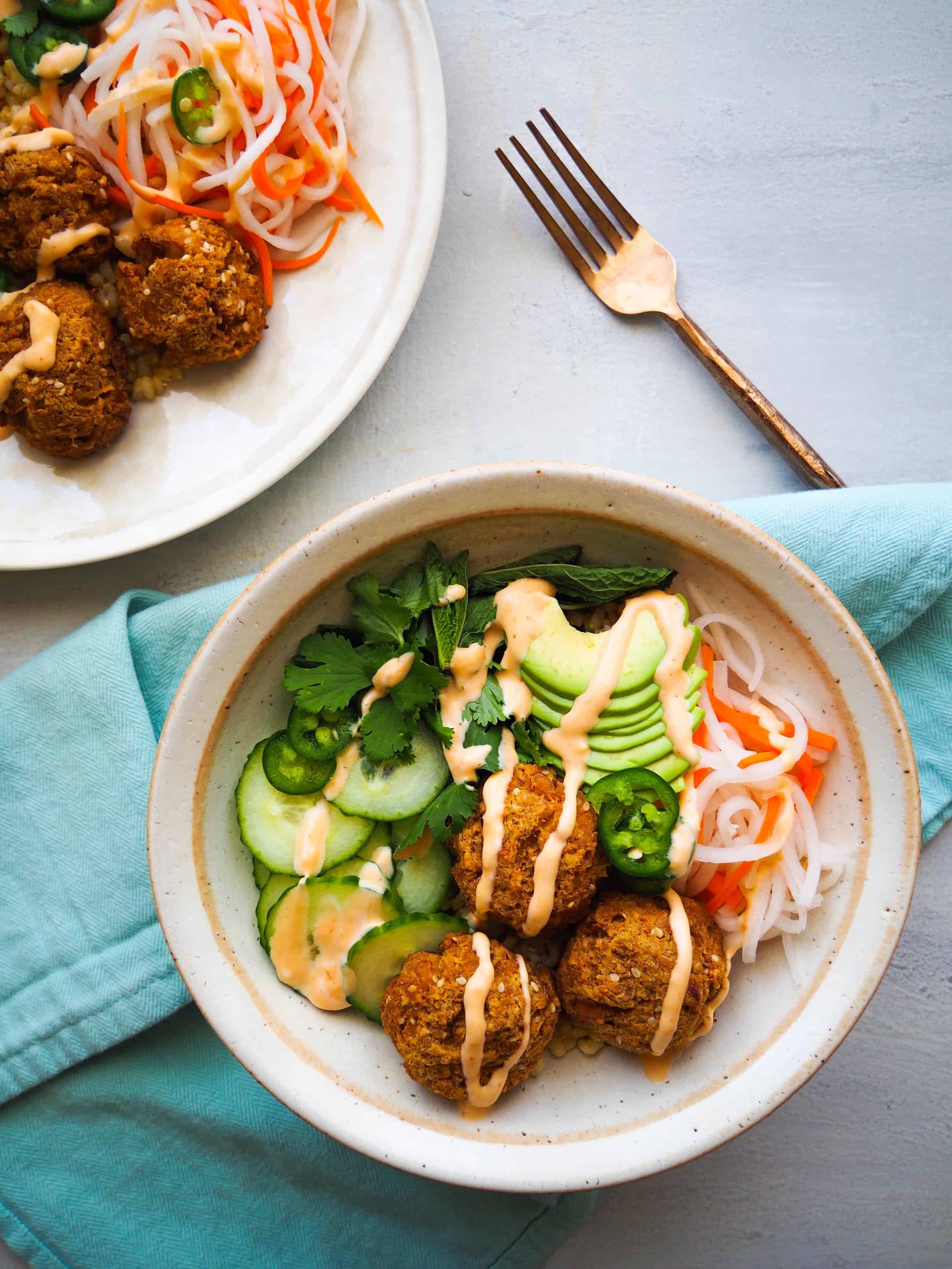 Bowl recipes.Banh Mi Bowl with tofu meatballs in white bowl with blue napkin against grey background.