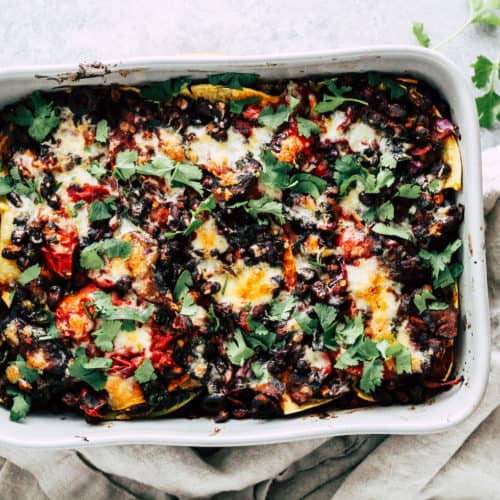 Overhead photo of black bean taco bake in grey ceramic baking dish with cream linen napkin.