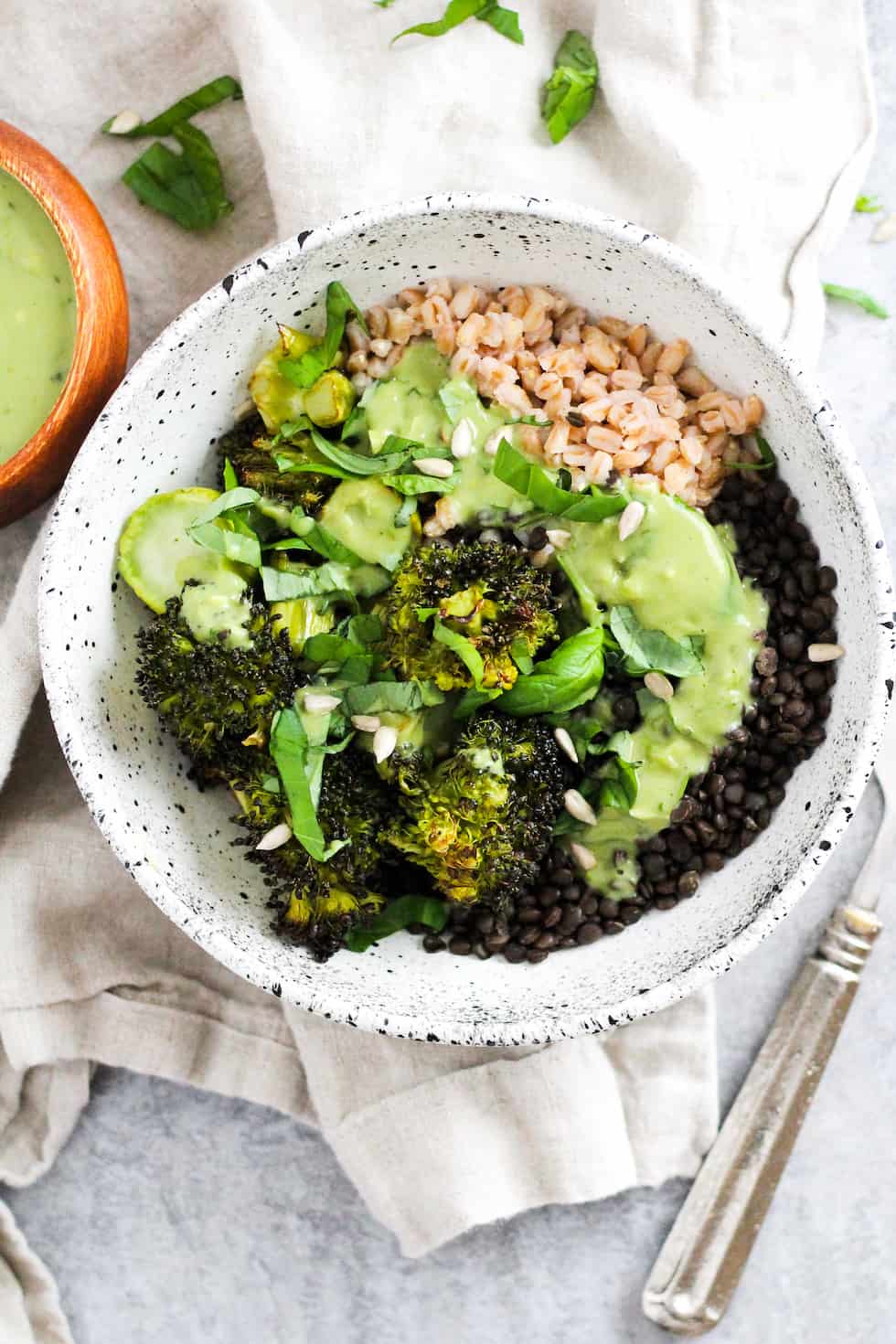 Lentil grain bowls with matcha dressing in white ceramic bowl with cream napkin.