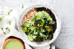 Horizontal images of lentil grain bowl with green matcha dressing. Small wood bowl of dressing on the side.