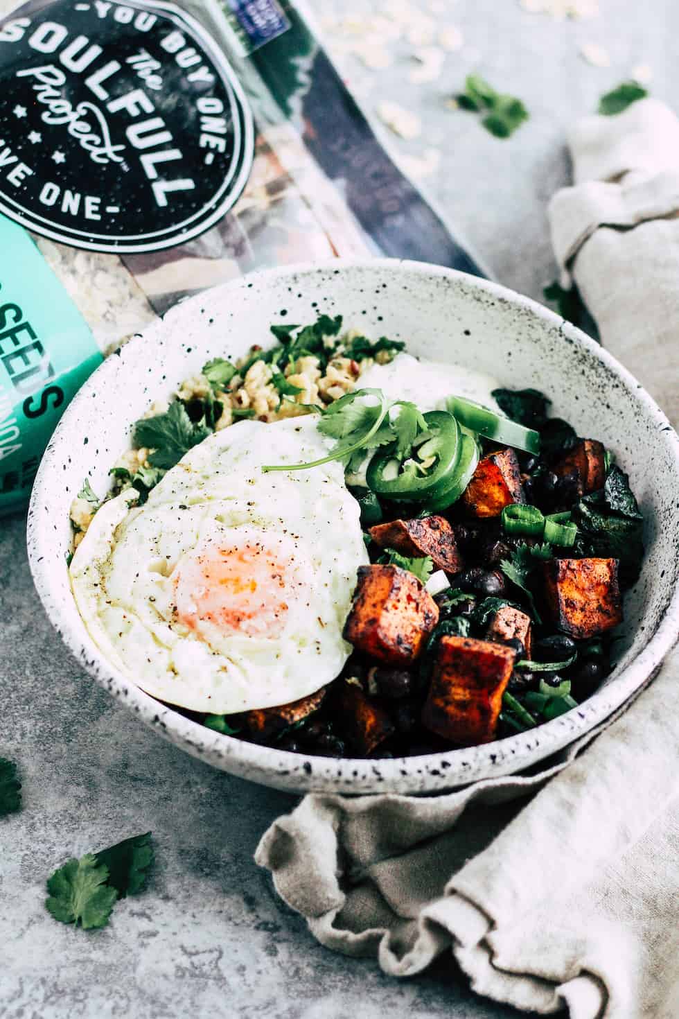 Breakfast burrito bowl in white ceramic bowl with bag of The Soulfull Project oats.