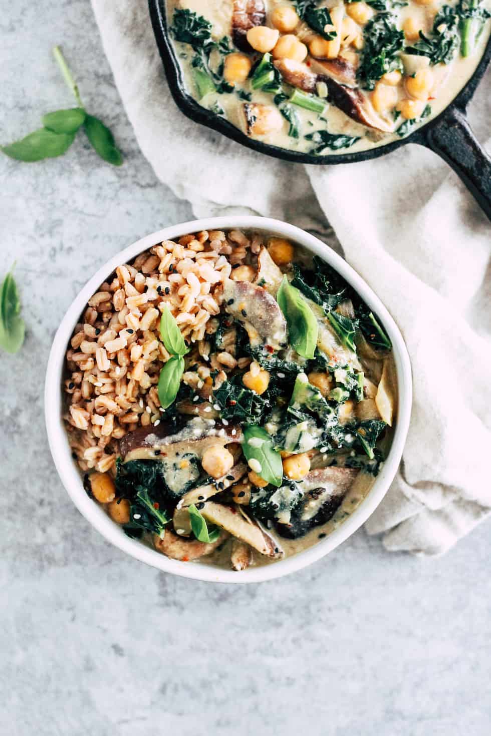 Shiitake mushroom bowls with skillet of creamy miso sauce against grey background with cream napkin.