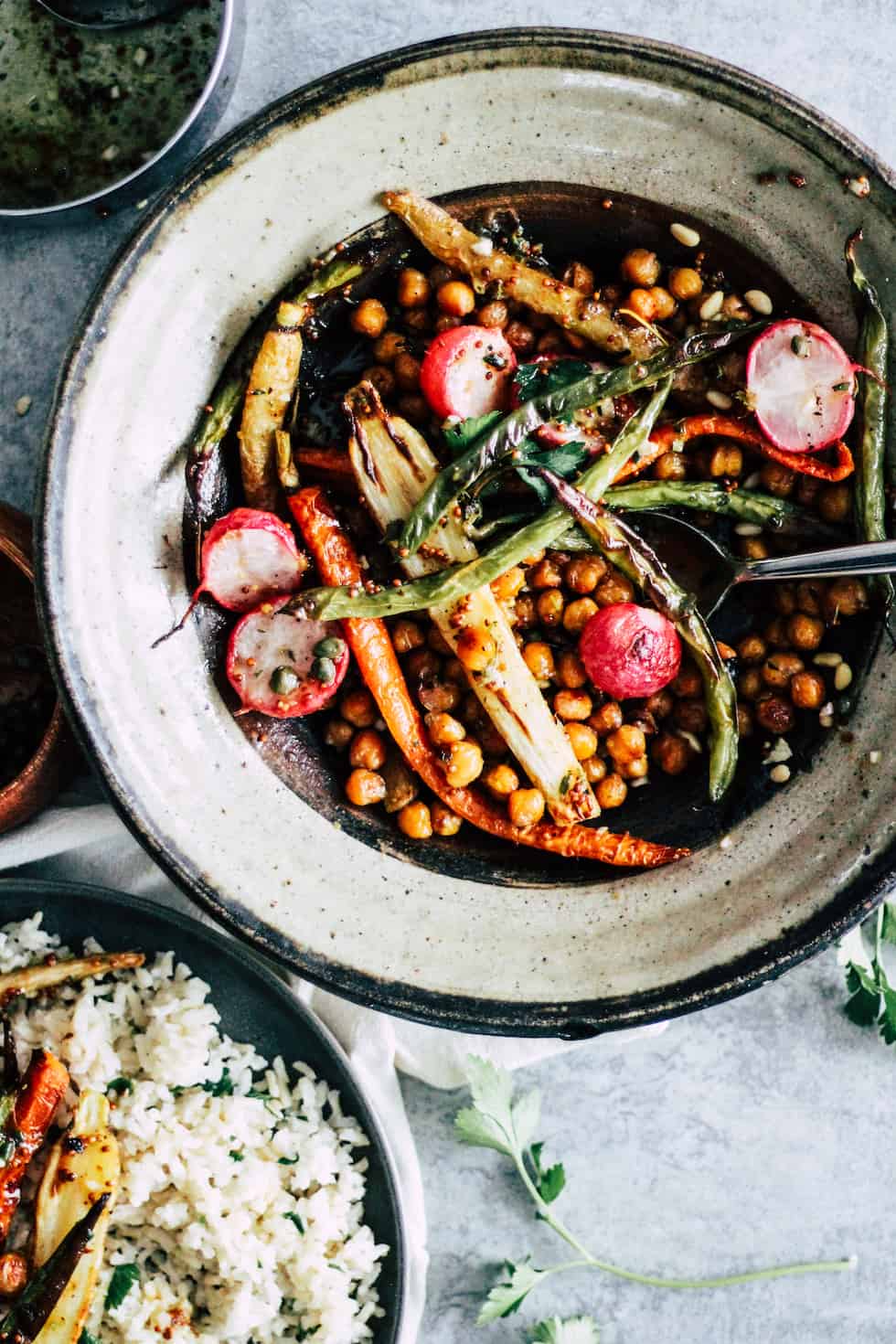 Bowl of chickpea sheet pan dinner with carrots, green beans and rice in clay bowl.