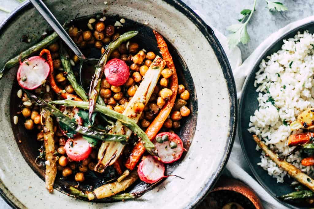 Chickpeas, carrots, and radishes in a stone bowl with rice.