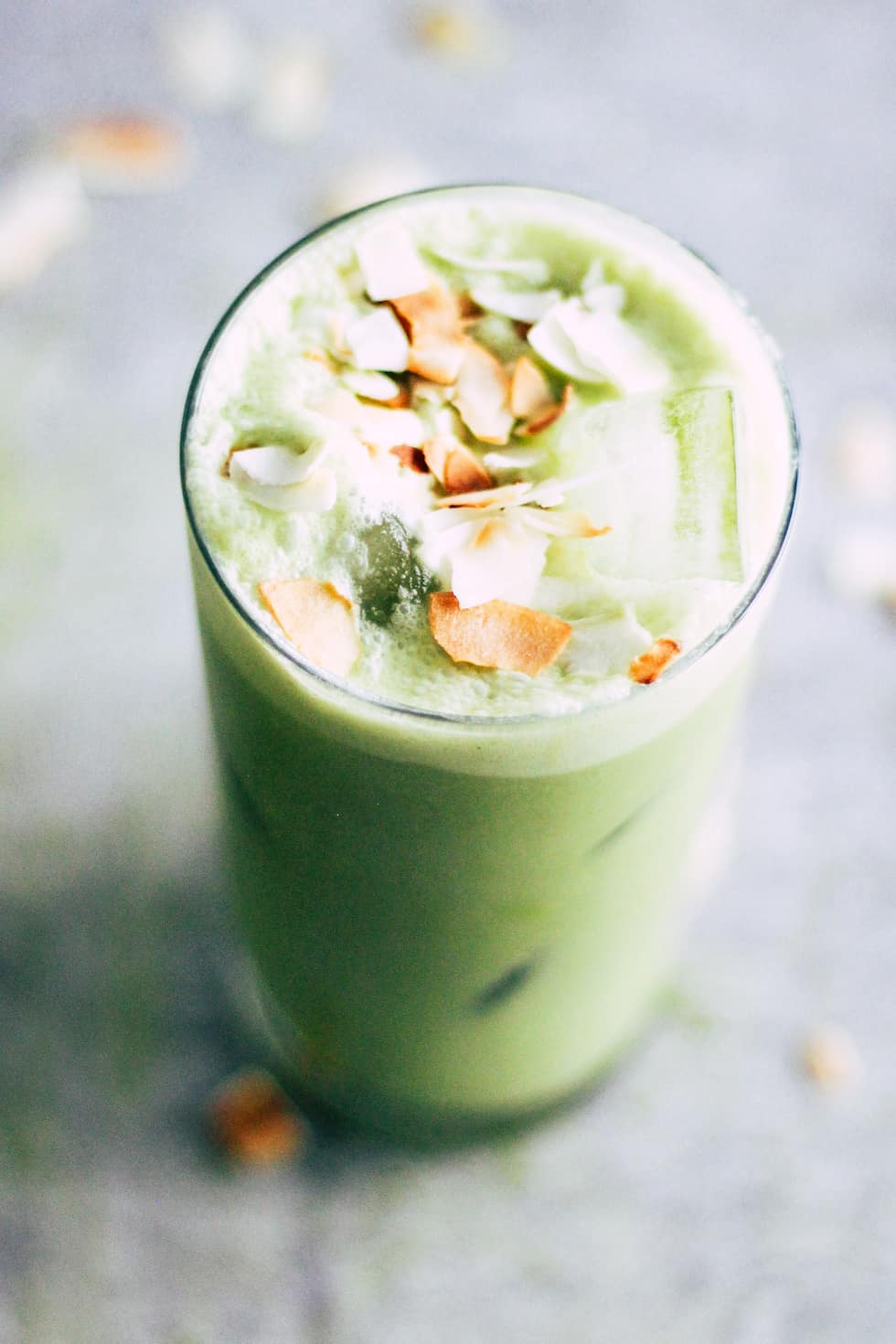 Toasted Coconut Iced Matcha Latte in glass topped with toasted coconut pieces.