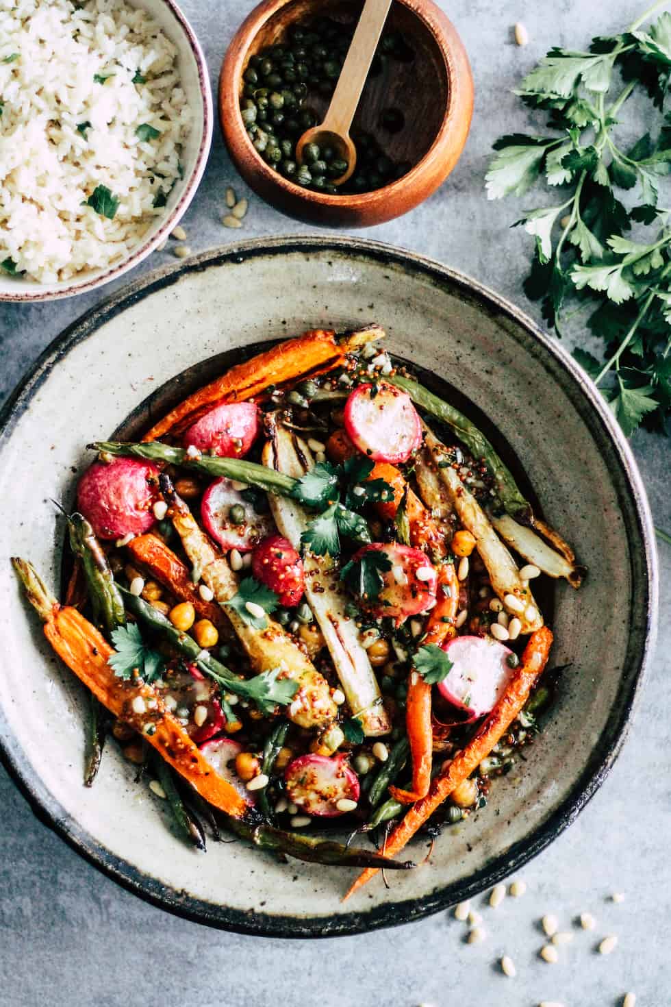 Chickpeas, carrots, and green beans in a stone bowl with smaller bowl of rice and herbs.