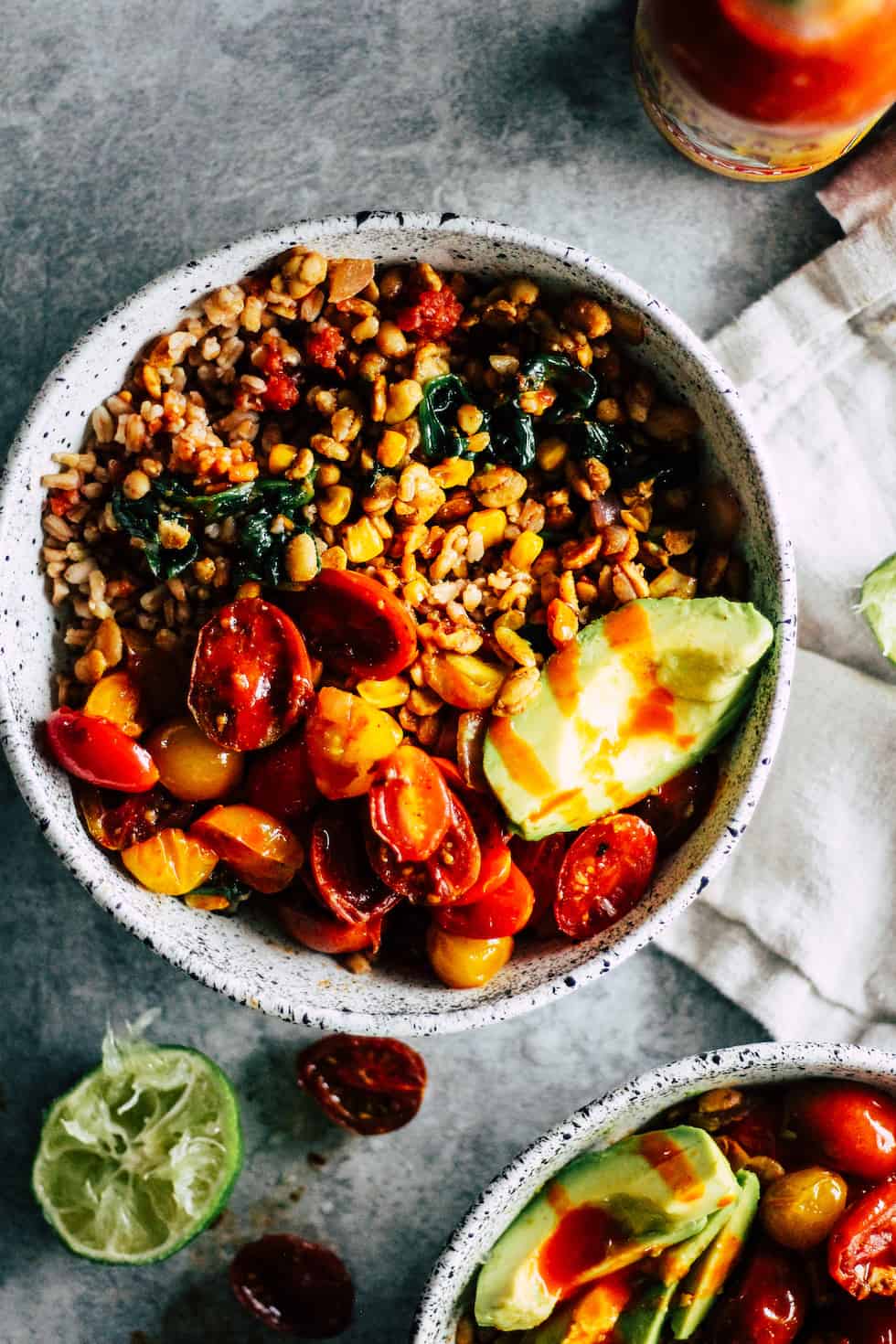 Tempeh Burrito Bowls in white ceramic dish with hot sauce and lime.