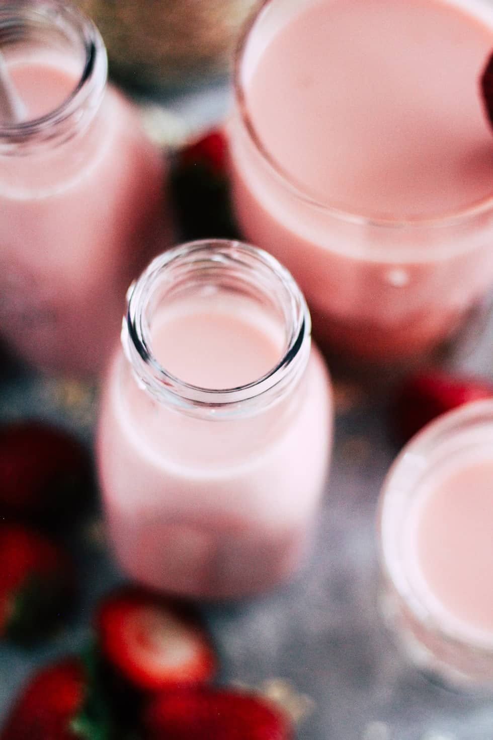 Milk jars filled with strawberry oat milk.