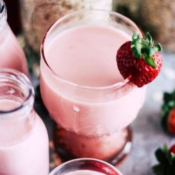 Homemade strawberry oat milk garnished with a fresh strawberry.