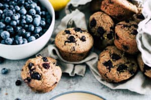 Blueberry muffins in a linen napkin next to a bowl of fresh blueberries.
