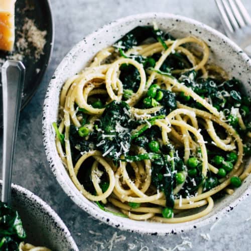 Spinach Cacio e Pepe in ceramic bowl with pecorino romano cheese.