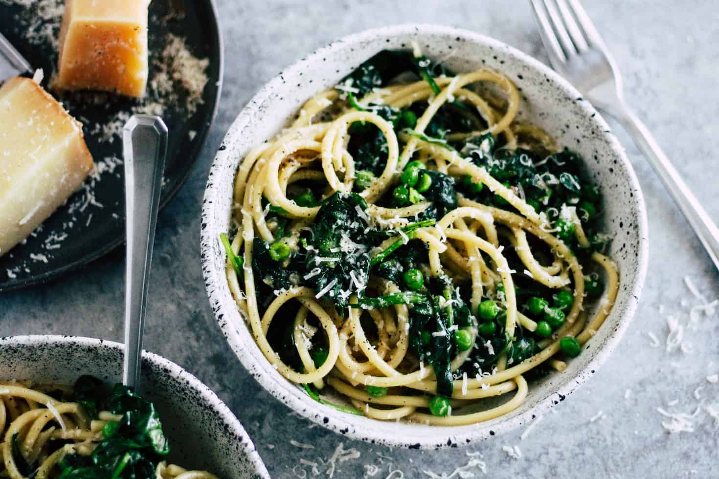 Spinach Cacio e Pepe in ceramic bowl with pecorino romano cheese.