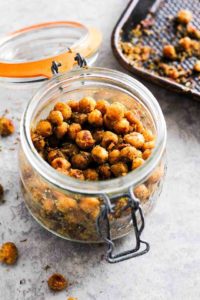 Mason jar filled with roasted chickpeas with baking pan in background.