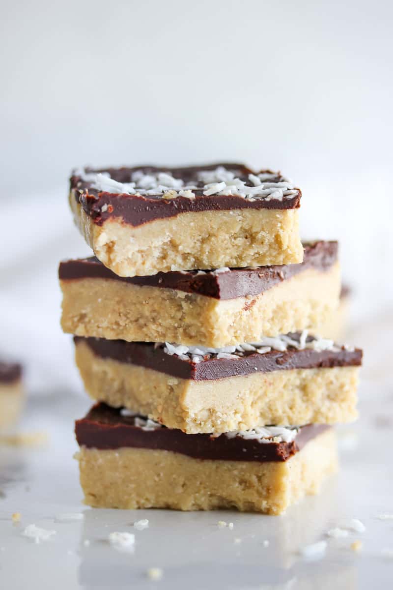 Raw coconut bars stacked against white background.