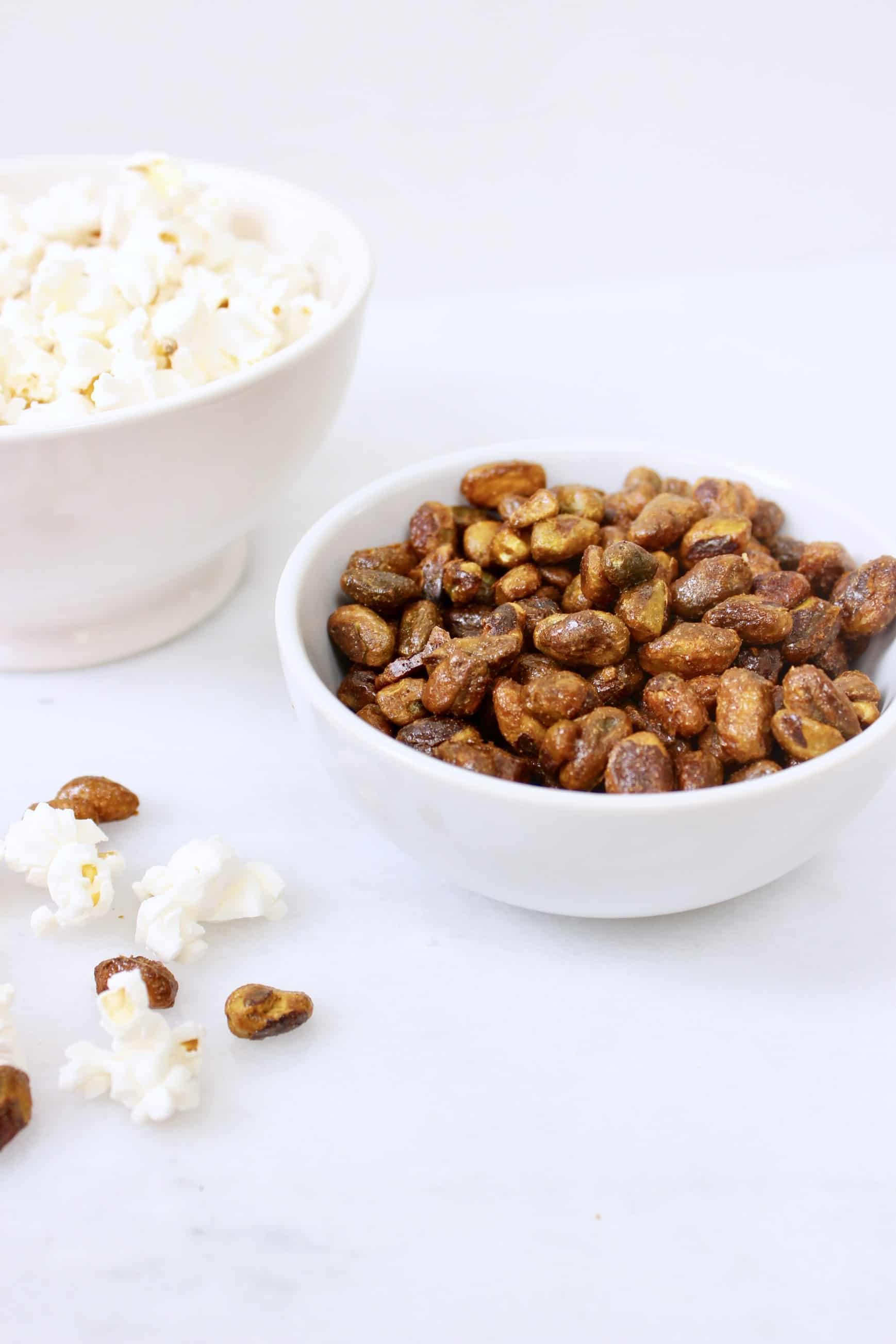 Candied nuts in white bowl against white background.