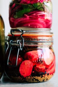 Glass jar filled with radish quick pickles and pickled red onions on top.