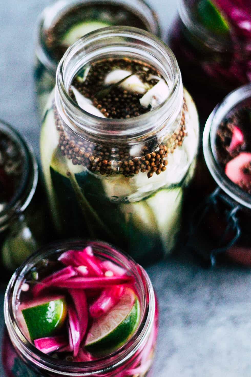 Pickled vegetables in mason jars on grey countertop.