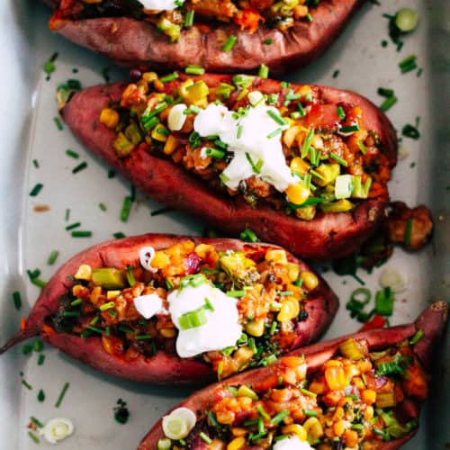 Baking dish with four loaded sweet potatoes.